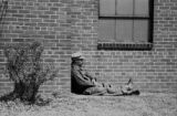 Jasper Wood Collection: Man taking nap against building