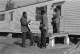 Recruiter interviewing family outside a mobile home.