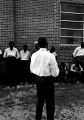 Stokely Carmichael and others, standing against the wall of a brick church building in Prattville, Alabama, during a meeting of the Autauga County Improvement Association.