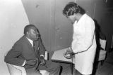 Barbara Howard Flowers, staff member at the Southern Courier, speaking to a man in a lounge at the Laicos Club in Montgomery, Alabama.