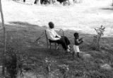 Elderly man and young boy in the yard of a house, observing a march in Prattville, Alabama, during a demonstration sponsored by the Autauga County Improvement Association.