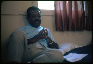 Rev. Ralph Abernathy seated on a hotel room bed