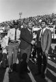 Muhammad Ali shaking hands with a man on the football field during homecoming activities for Alabama State College on Thanksgiving Day in Montgomery, Alabama.