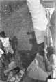 Man standing in a trailer filled with cotton, reaching down to lift a bag that has just been weighed.