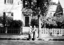 Two unidentified women standing in front of a house on the street