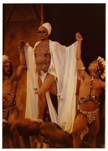 Performance photo of Eartha Kitt in a white turban and three men.] [color photoprint