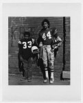 [Lower West Side, Buffalo, N.Y. Jose Eskelin, Puerto Rican desent, wearing football uniform, and an unidentified African-American boy, full-length portrait, standing, facing front, holding helmets]