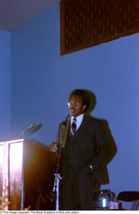 Photograph of man speaking into microphone at conference