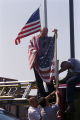 Fireman S. L. McAdams holding an American flag while his colleagues secure it to an engine at Fire Station #12 in Birmingham, Alabama, after observing a moment of silence honoring the victims of the September 11 terrorist attacks.