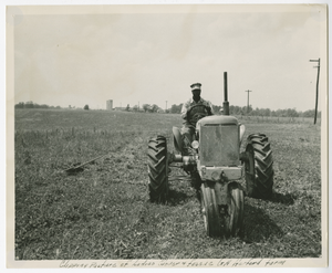 Photograph of an African American agricultural worker riding a lawnmower and clipping pasture of Ladino clover and fescue on the farm of G.A. Herford, Columbia County, Georgia, 1952-1957?