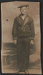 [William LeRoy Parker of USS Rosedale in uniform in front of painted backdrop]