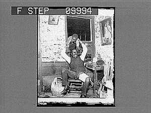 African American man playing with mischievous boy in rustic home. Active no. 21953 : half-stereo photonegative.