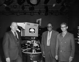 Three men smiling with a camera