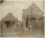 [African American boy seated on porch of house, another African American boy standing with bicycle on porch of another house, with two young African American women on steps, Georgia]