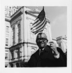 Mississippi State Sovereignty Commission photograph of an African American man holding an American flag and standing in front of the Georgia State Capitol during a demonstration, Atlanta, Georgia, 1960s