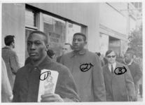 Mississippi State Sovereignty Commission photograph of Larry Hanshaw, Malcolm Taylor and Hunter Morey (left to right) standing in front of a Western Union storefront with other unidentified demonstrators during an Anti-Vietnam War demonstration protesting Secretary of Defense Robert McNamara's visit to Jackson, Mississippi, 1967 February 24