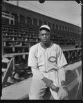 Baseball pitcher Satchel Page seated next to bleachers, Los Angeles, circa 1933