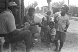 Thumbnail for Man, woman, and children, eating and drinking outside a barn or shed near Mount Meigs in Montgomery County, Alabama.