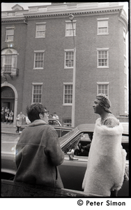 Umoja (Black student union) activist standing by car, wrapped in a sheepskin and talking to a white onlooker, at site of occupied administration building, Boston University
