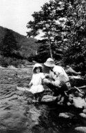 An unidentified man and little girl in a stream