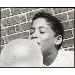 Close-up of an African American boy from the Roxbury Boys' Club blowing a bubble with gum