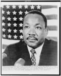 Thumbnail for [Dr. Martin Luther King, Jr., head-and-shoulders portrait, seated, facing front, in front of American flag, at a St. Augustine, Florida press conference]