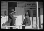 Mr. Jones, one of the owners of Marcella Plantation, with manager of Goodhope Plantation talking to one of Negro tenants on porch of Plantation store and post office, Mileston, Mississippi Delta, Mississippi