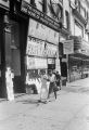 Two girls walking down the sidewalk in front of The House of Common Sense and Home of Proper Propaganda in Harlem.