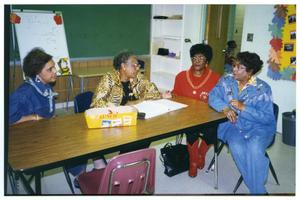 Four Older Women Seated at Desk