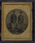 [Two unidentified young soldiers in Union shell jackets and forage caps in front of painted backdrop showing plantation]