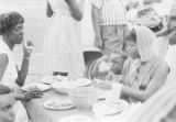 Marie Tarver, Yolanda Dabney, and Bernice Simon eating at a picnic table during a cookout in the Madison Park community in Montgomery, Alabama.