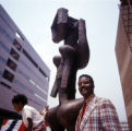 John W. Rhoden sitting in front of his sculpture with a child