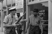 Police officer speaking to an African American man in front of a business down the street from 16th Street Baptist Church in Birmingham, Alabama, after the church was bombed.