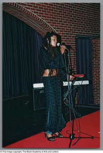 Photograph of artist Rhea singing into microphone