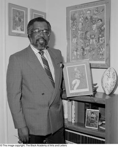 Abner Haynes posing with football memorabilia