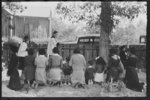 Negroes kneeling at graves of relatives, and being blessed by priest with holy water, New Roads, Louisiana