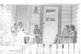 Group of girls sitting on the front porch of a wooden house in Newtown, a neighborhood in Montgomery, Alabama.