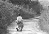 Young boy walking down a dirt road near Mount Meigs in Montgomery County, Alabama.