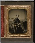 [Unidentified sailor seated in front of a painted backdrop showing nautical scene, right arm resting on table draped with an American flag]