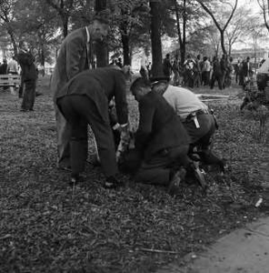 Police officer and three men restraining a civil rights demonstrator on the ground during a protest at Kelly Ingram Park in Birmingham, Alabama.