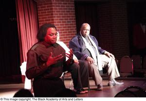 Curtis King speaking while performer and man sit on stage