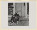 [African American man and his son are seated outside on concrete steps, Lower West Side, Buffalo]