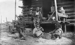 Children sitting on the porch of a log cabin