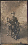 [Unidentified African American soldier in uniform with marksmanship qualification badge and campaign hat, with cigarette holder in front of painted backdrop]