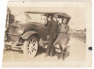 Photographic print of a man and woman standing in front of a car