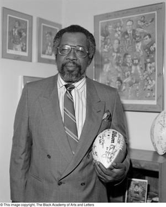 Abner Haynes posing with football memorabilia #2