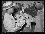 Two Negro men passing a young baby through a hoop to cure the "stretches" which are caused according to Negro superstition by a woman who is menstruating picking up a young baby. The baby must be passed through the hoop each morning for seven consecutive days. Picture taken near Jefferson, Texas