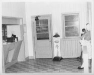 Mississippi State Sovereignty Commission photograph of an African American woman holding a baby while standing in the waiting area and ticket office of the Trailways bus depot, Winona, Mississippi, 1961 November 1