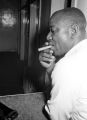 Charlie Marshall, a cook at the Laicos Club in Montgomery, Alabama, standing at a counter and smoking a cigar.