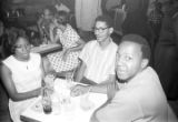 Barbara Howard Flowers and Robert Flowers seated with another man at a table at the Laicos Club in Montgomery, Alabama.